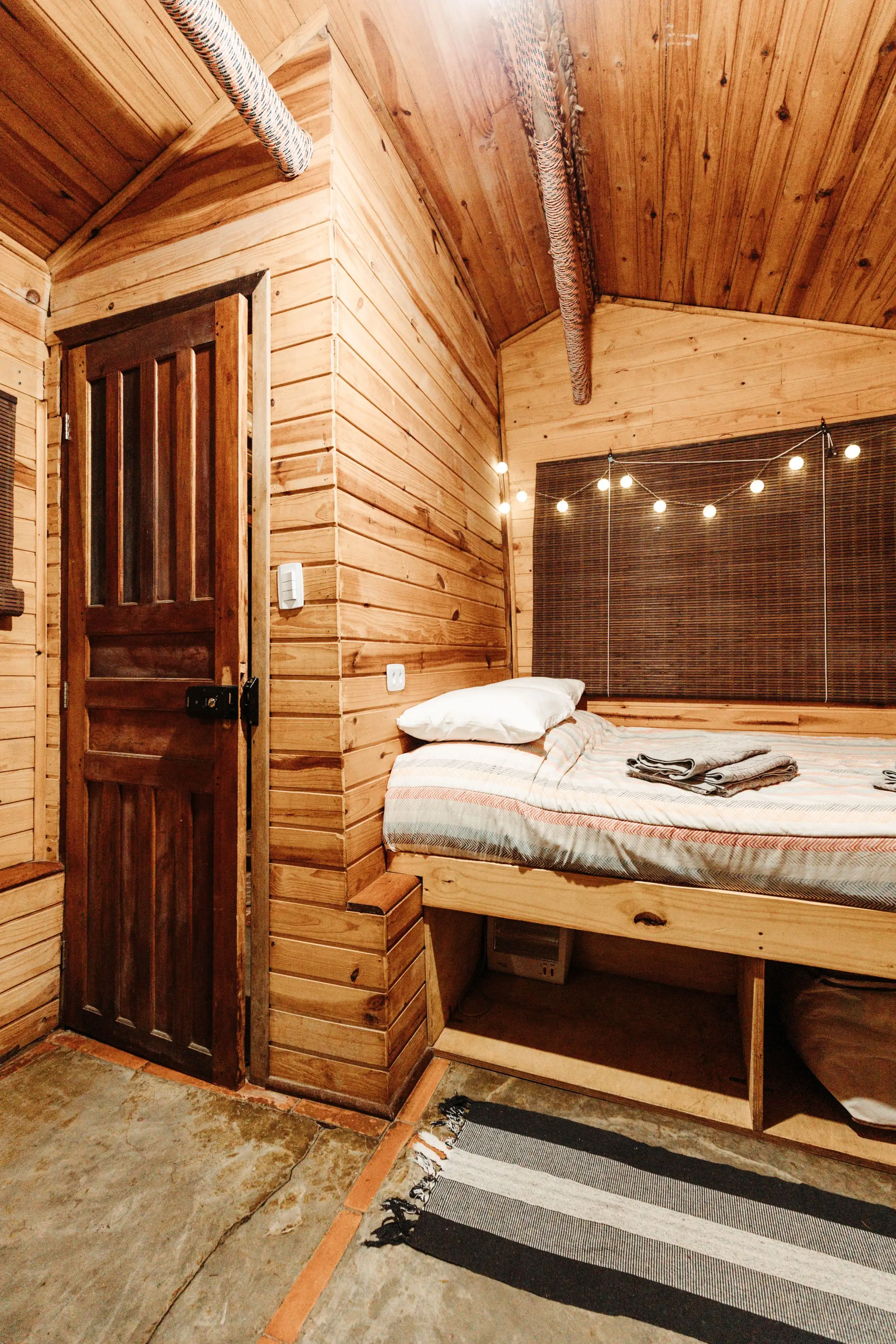 Recámara de madera con cama y foquitos