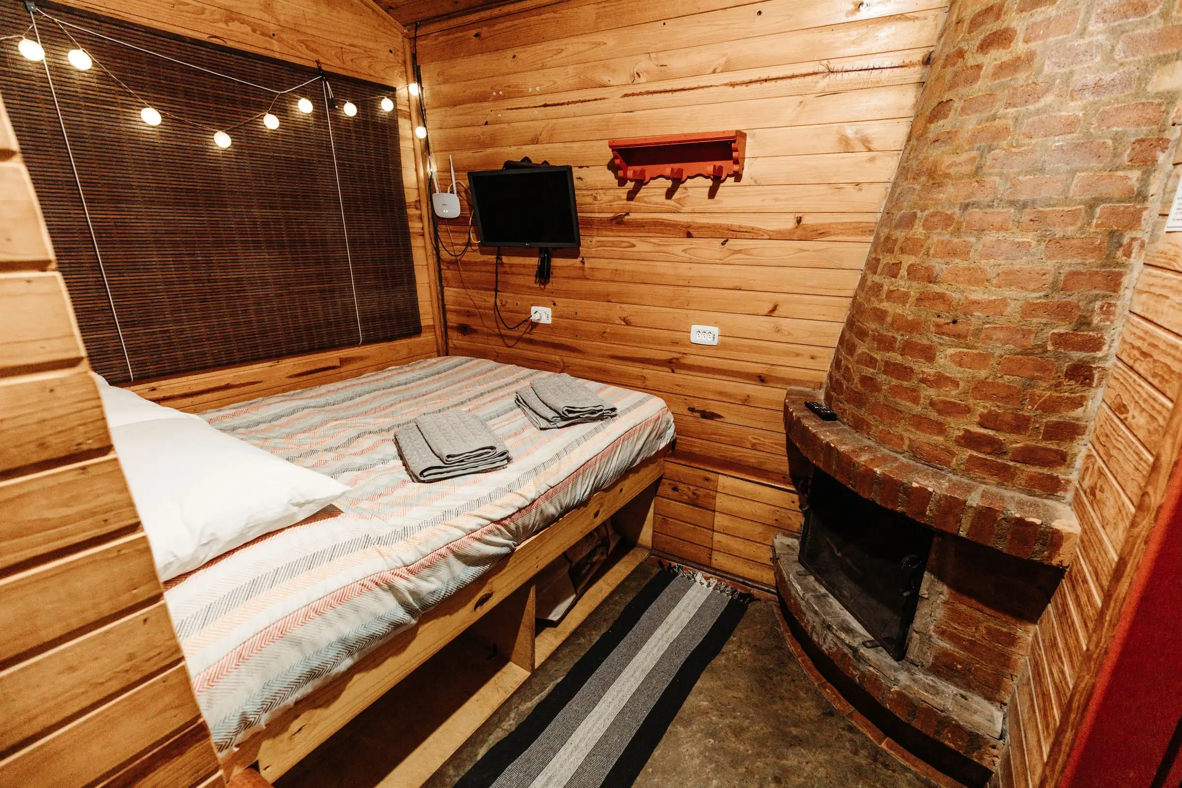 Recámara de madera con cama y chimenea de ladrillo