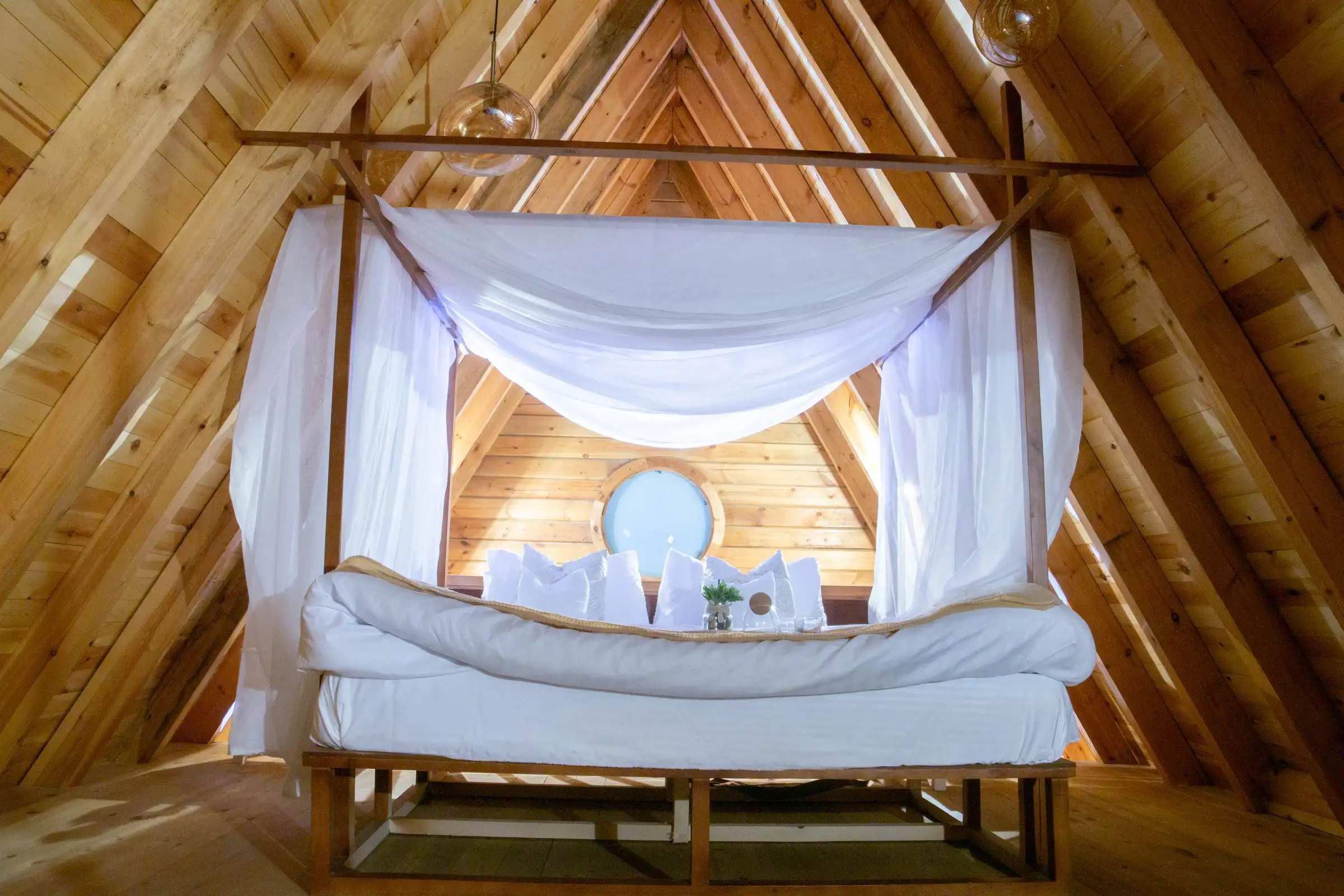 Cama en el tapanco, bajo el techo de madera inclinado